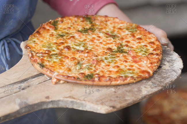 Countrywoman holding freshly baked pizza (from wood-fired oven)