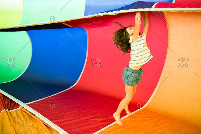 Little girl playing inside a colorful rainbow parachute