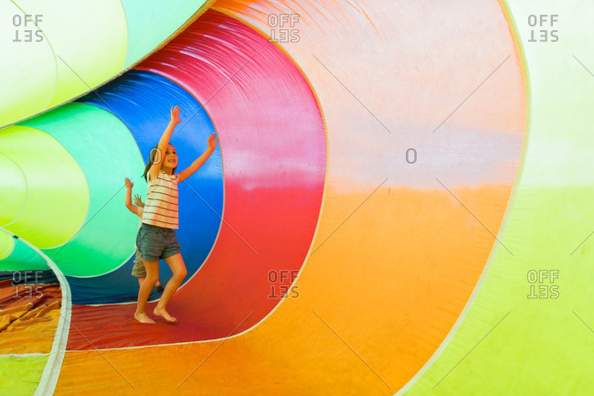 Boy and girl running around a colorful rainbow parachute