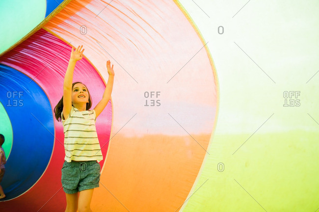 Girl playing inside an inflatable rainbow parachute