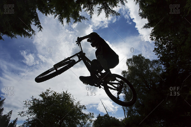 Silhouette Of Man Jumping On Mountain Bike In Gloucestershire, Uk
