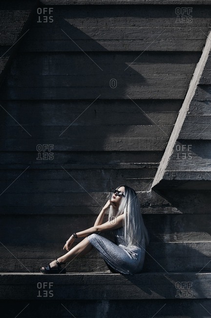 Woman with long silver hair posing against concrete wall background