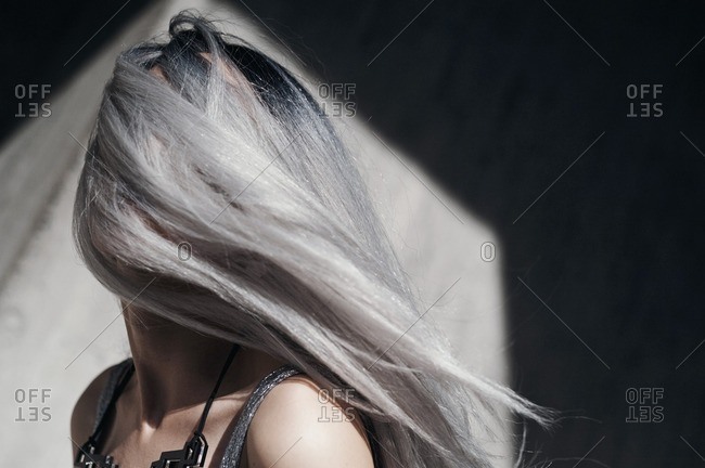 Woman with long silver hair blowing over her face