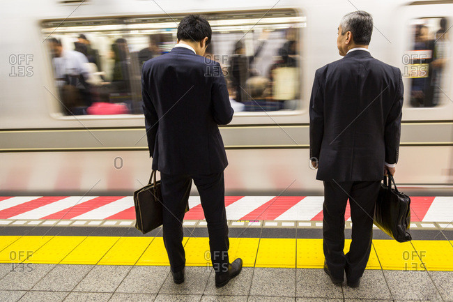 Two businessmen waiting for a train on the Tokyo Metro, Tokyo, Japan, Asia