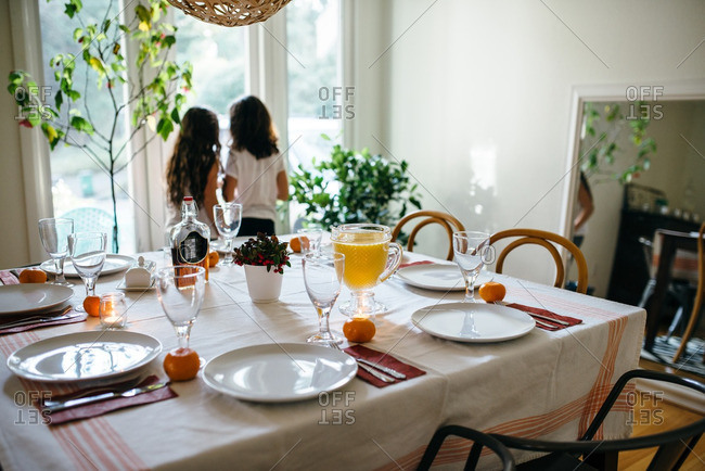 Girls standing at a window near a table set for Christmas breakfast