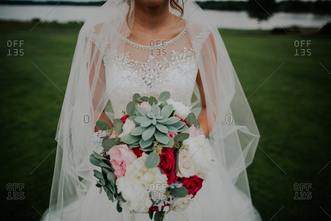Mid-section of bride holding bouquet