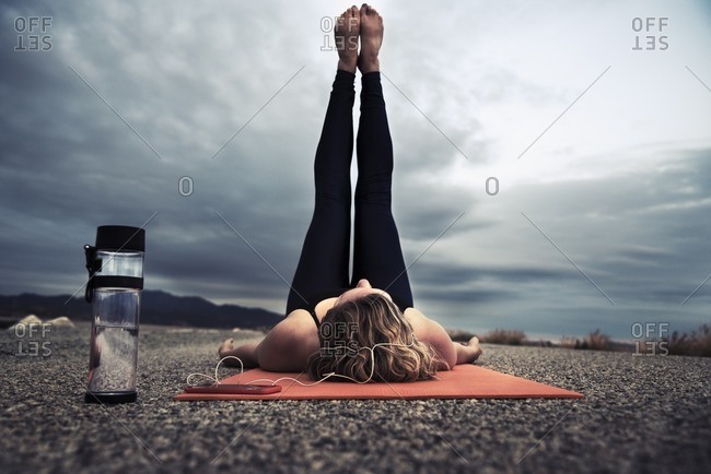 Woman lying on ground with feet in the air while listening to music