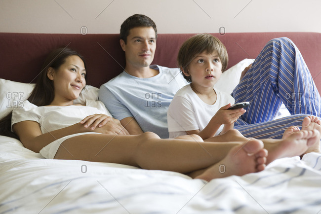 Family watching TV in bed