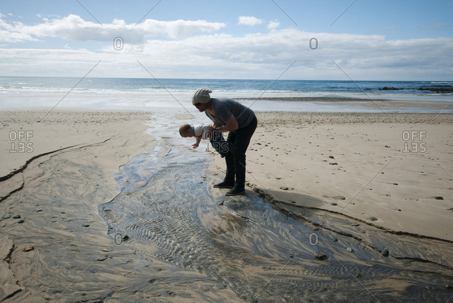 Father and toddler looking at rippled sand at the beach