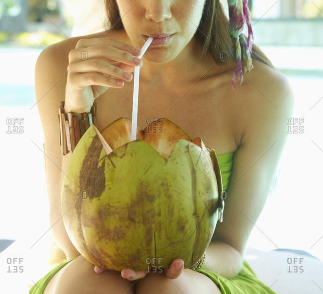 Pacific Islander woman drinking fresh coconut
