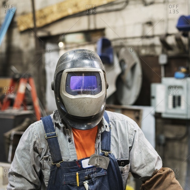 Caucasian worker wearing welding mask in factory