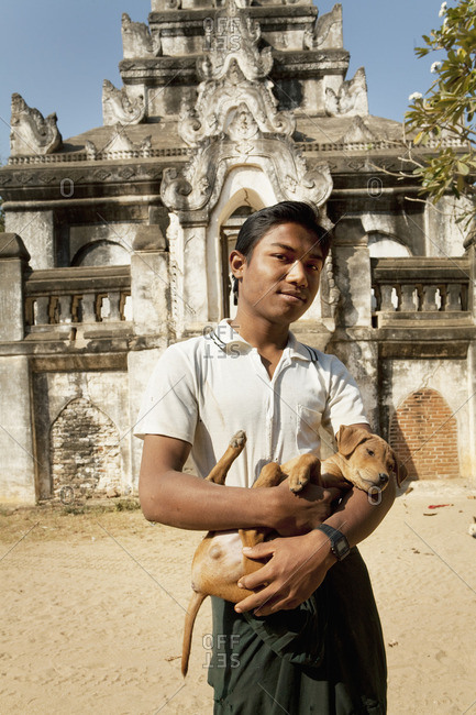 Asian boy holding dog outside temple