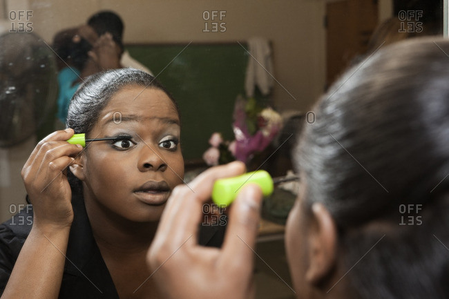 African American girl putting on mascara backstage
