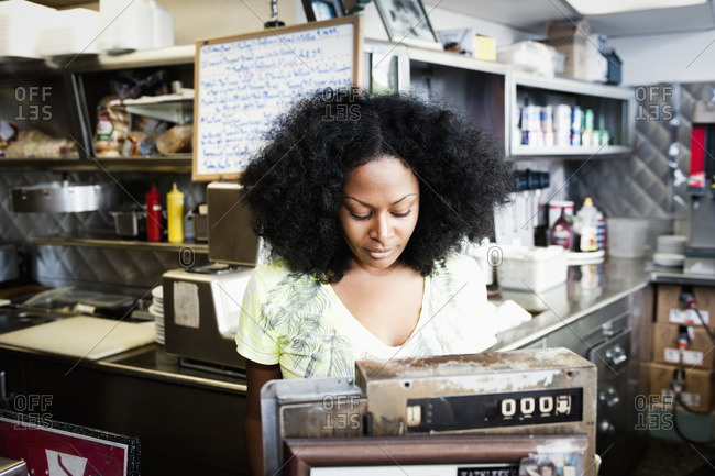 Mixed race waitress at cash register in diner