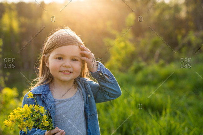 Little girl holding a bunch of yellow flowers at sunset
