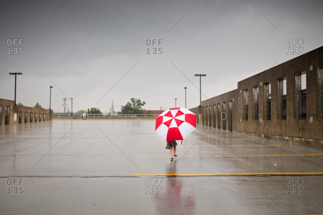 Little girl running in rain with umbrella