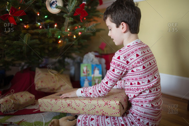 Boy sitting with gift on his lap at Christmas tree