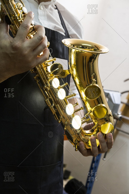 Instrument maker holding a saxophone in his workshop