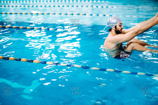 Man in swimming pool holding onto poolside
