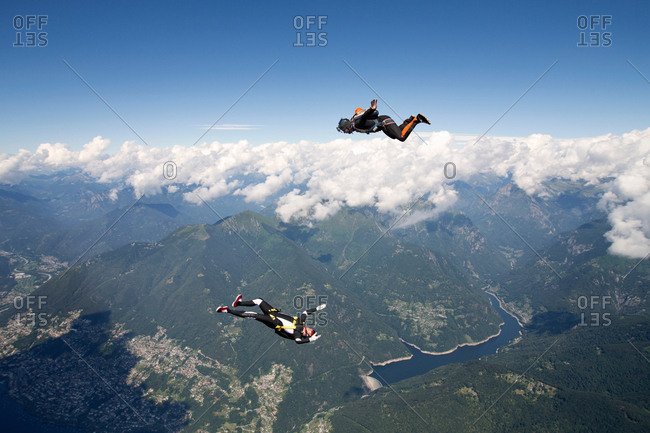 Freestyle skydiving team training together. One man  performing air-ballet, another jumper is filming with video camera on helmet, Locarno, Tessin, Switzerland