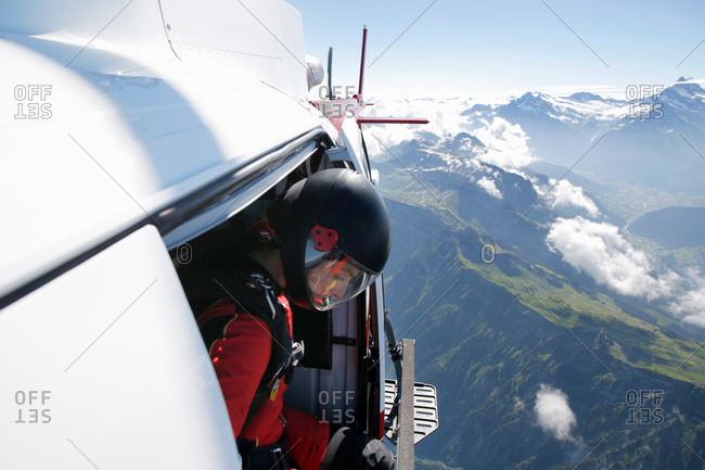 Female sky diver in helicopter checking for exit over mountain, Interlaken, Berne, Switzerland