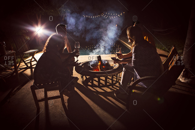Four mature adults sitting together around patio fire at night