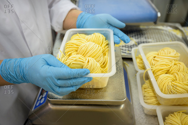 Worker weighing portions of tagliatelle in pasta factory, close up