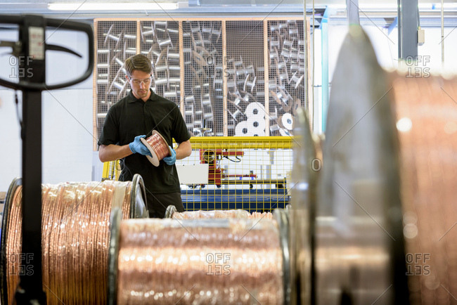 Worker inspecting copper cable in cable factory