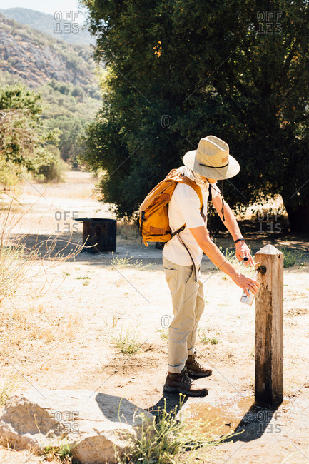 Man filling water bottle at outdoor tap, Malibu Canyon, California, USA