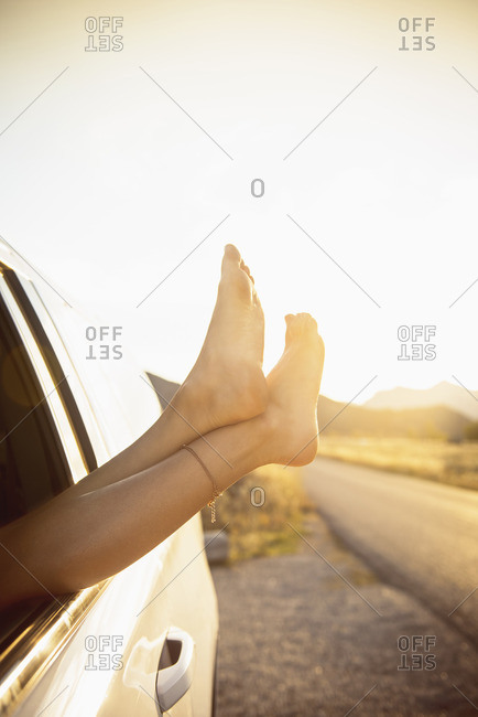 Hispanic woman hanging feet out car window