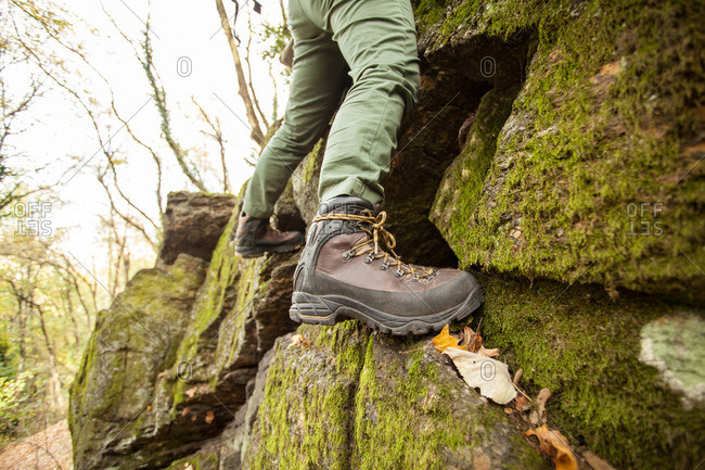 Feet of person climbing forest boulder