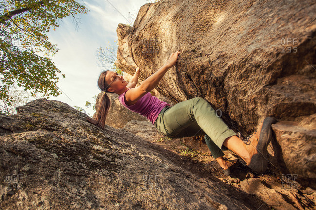 Woman climbing by rock crevice