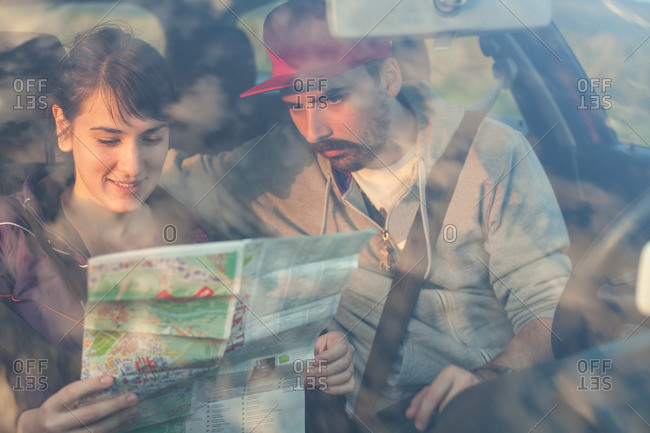 Young couple checking map in car