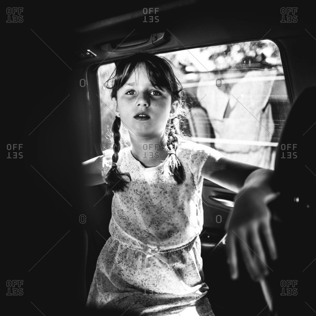 Portrait of a girl in the back seat of a car with her back reflected in the window