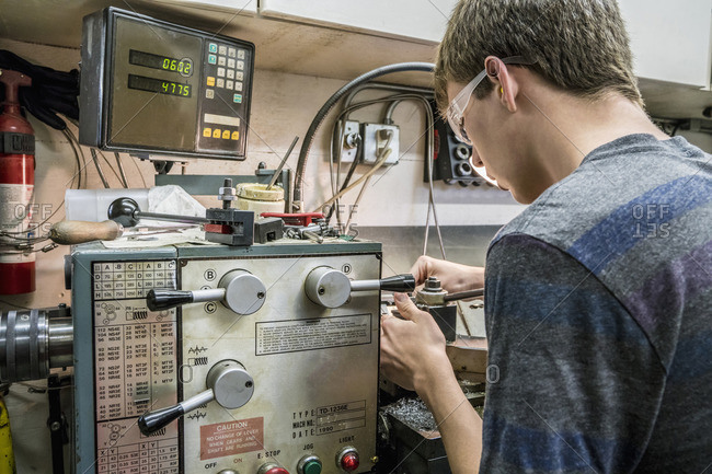 Caucasian students adjusting machinery in workshop
