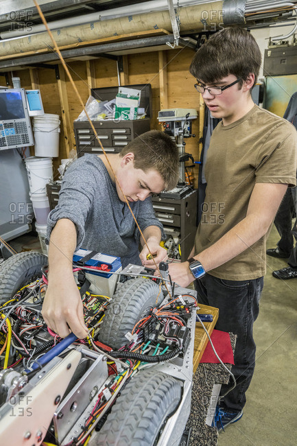 Caucasian robotics students adjusting machinery