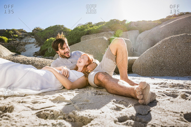 Couple lying on beach, head in lap smiling