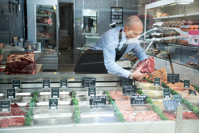 Butcher preparing window display in butcher\'s shop