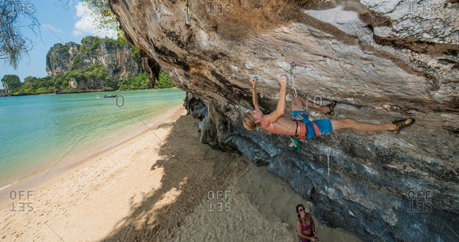 Rock climber climbing rock face at beach, Tonsai, Railway Beach, Krabi, Thailand