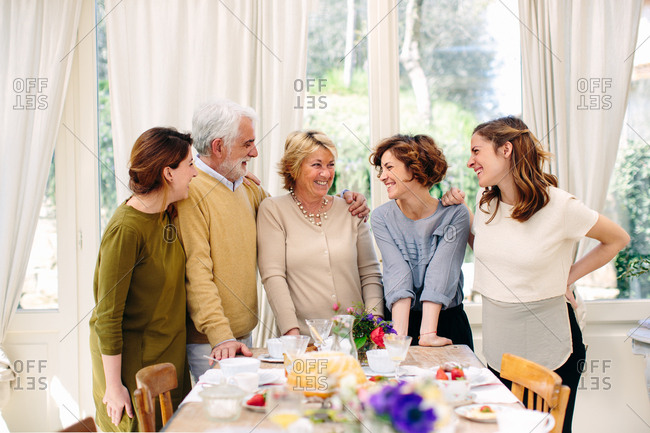Italian senior couple and three daughters standing at breakfast table