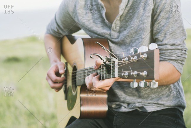 Close up of young man playing an acoustic guitar outside