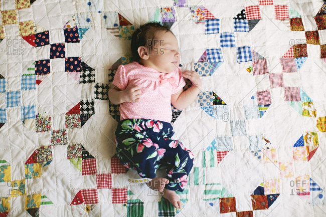 Sleeping baby lying on a colorful quilt