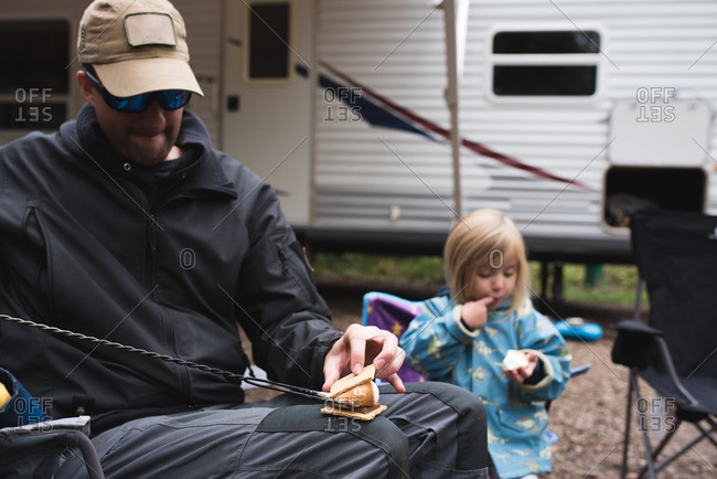 Father and daughter enjoying s\'mores at a campground