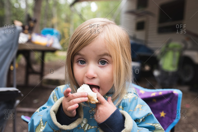 Little girl eating s\'mores in a camping chair
