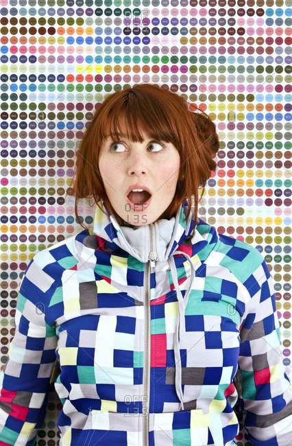 Young woman wearing patterned jacket in front of dotted wall