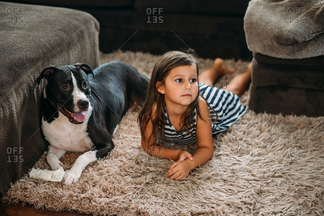 Girl lying on carpet with pet dog