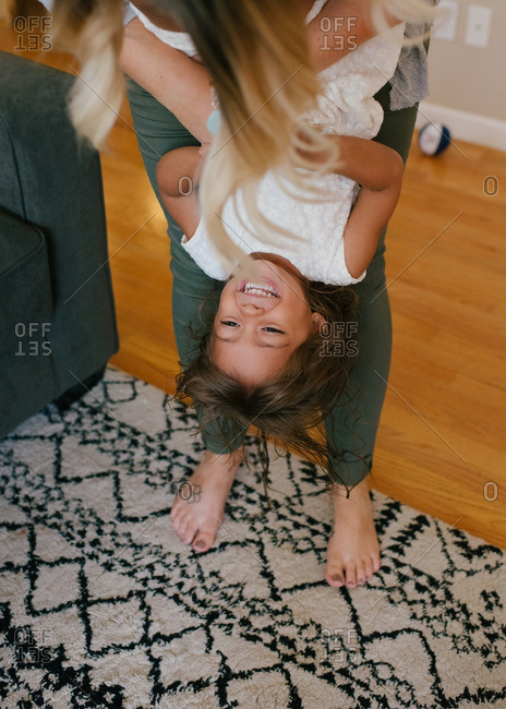 Mother holding her daughter upside down