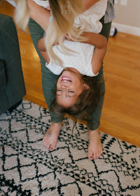 Mother playing with her daughter while holding her upside down