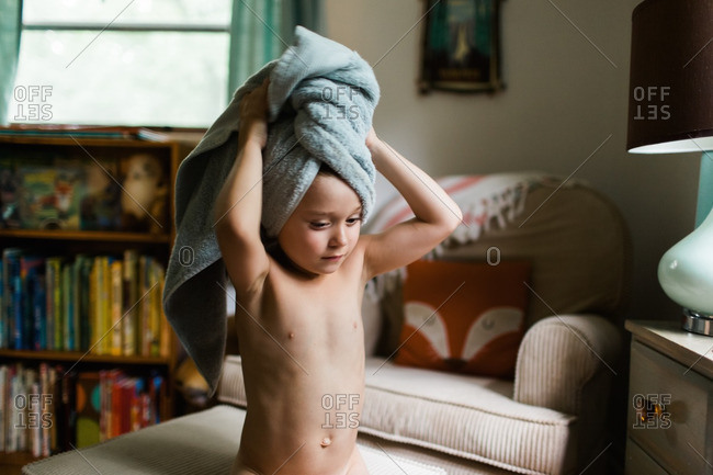 Boy sitting on an foot stool drying his hair