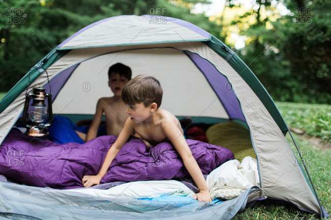 Brothers hanging out in a tent in a backyard